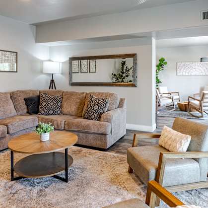 A living room with a large sectional sofa and a coffee table in the center.
