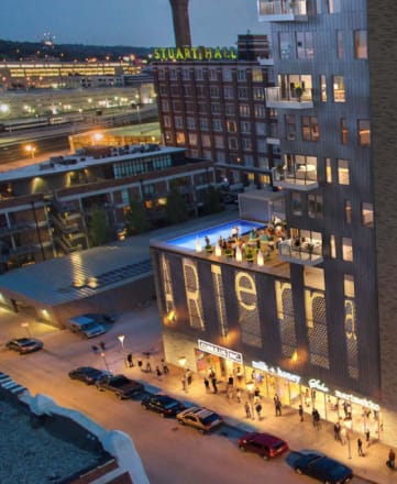 an aerial view of a tall building at night with people walking on the sidewalk