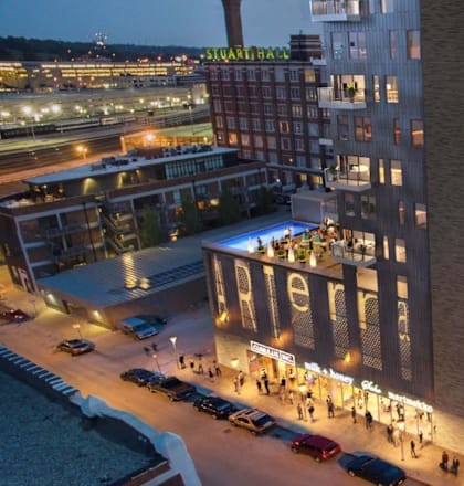 an aerial view of a tall building at night with people walking on the sidewalk