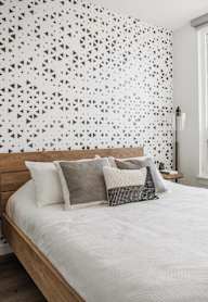 A bedroom with a bed, nightstand, and a wall with a black and white geometric pattern.at Axle, Seattle Washington