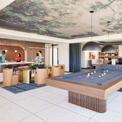 A billiard table is in the middle of a room with people standing around it.