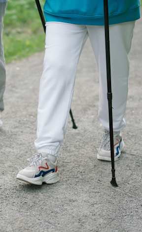 Two people walking on a path with one person using a cane.