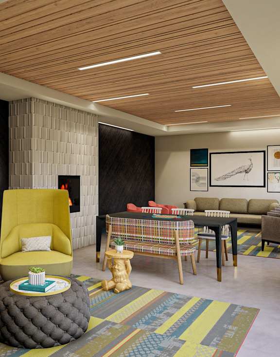 A modern living room with a yellow chair and a round ottoman at The Bessemer at Seward Commons Apartments, Minneapolis, MN,  55404