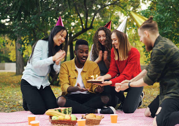A group of people celebrating a birthday outdoors.