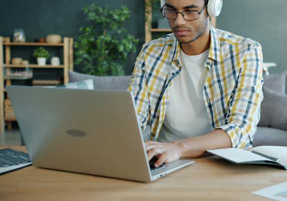 A person in a plaid shirt is using a laptop.