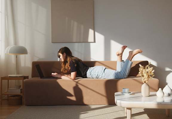 a woman laying on a couch with a laptop