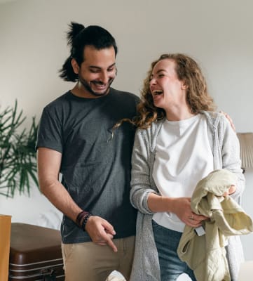 Laughing couple packing boxes inside a living room