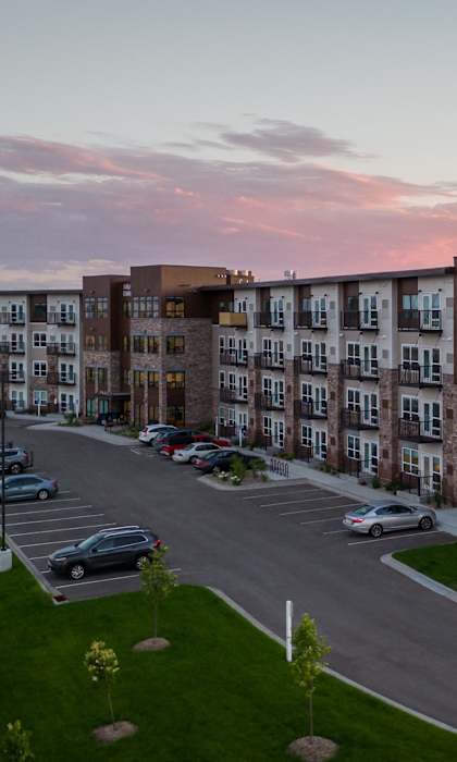 A large apartment complex with a parking lot in front.