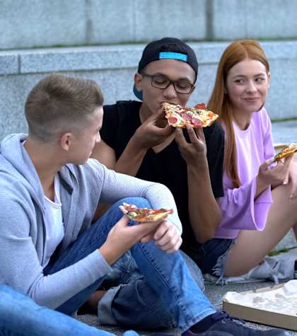 Four people eating pizza on the steps.