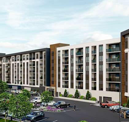 A modern apartment complex with a parking lot in front.