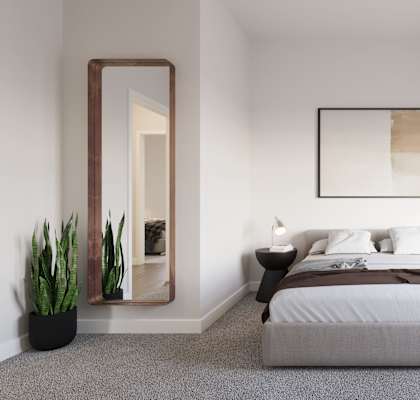 A bedroom with a large bed, a mirror, and a potted plant.at The Landing at Hub City, Plymouth, 53073