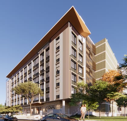 A modern building with a brown roof and beige walls is surrounded by trees and has cars parked in front.