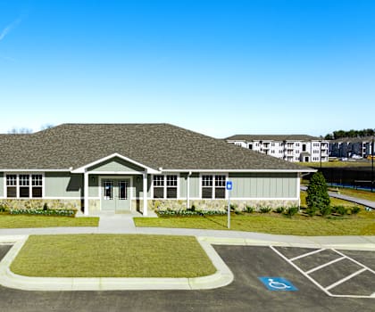 the front of a building with a parking lot and grass