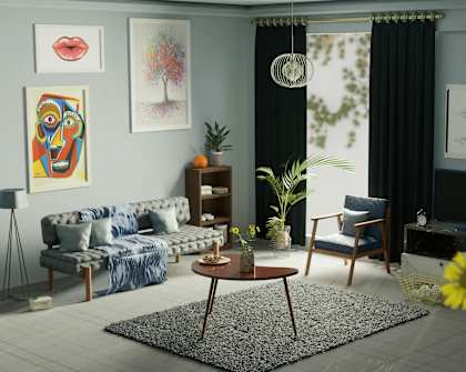 A living room with a grey sofa, a blue cushion, a wooden coffee table, a TV, a clock, a potted plant, a vase with yellow flowers, and a framed picture on the wall.