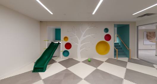 A room with a green slide and a tree mural on the wall.