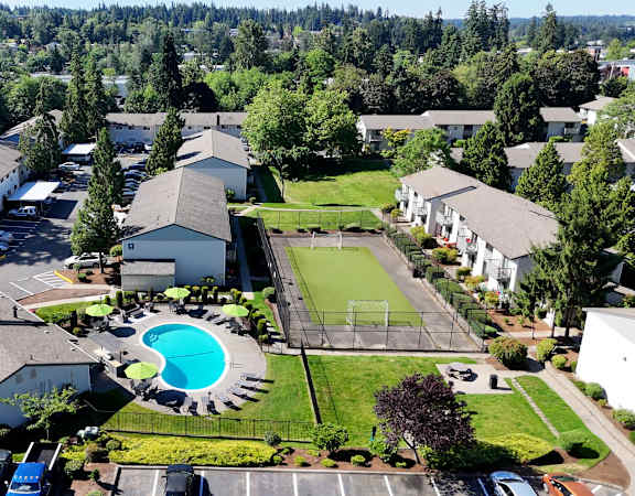 A bird's eye view of a residential area with houses, a swimming pool, and a tennis court.