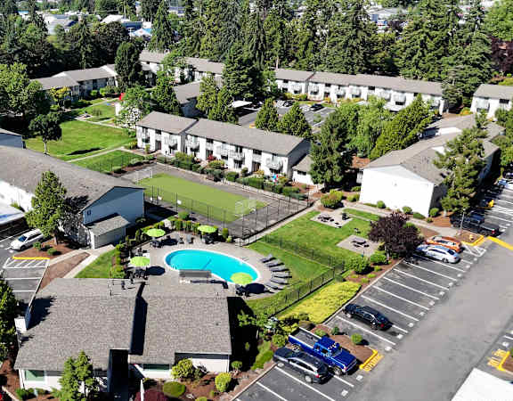 A large white building with a pool in the middle of a grassy area.