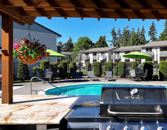 A pool with a grill on a table in the foreground.