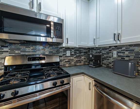 A modern kitchen with a stove, microwave, and toaster oven.