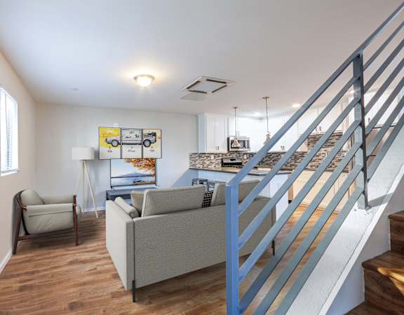 A living room with a couch, chair, and stairs.