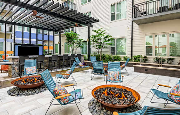 A patio with a fire pit and chairs.