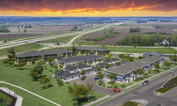 an aerial view of a building with a sunset in the background at The Residences Apartments at Bear Tree | DeForest, WI, DeForest