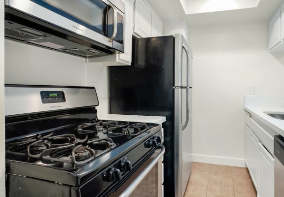 Apartment kitchen with stainless steel appliances, white counter tops, and white cabinets.
