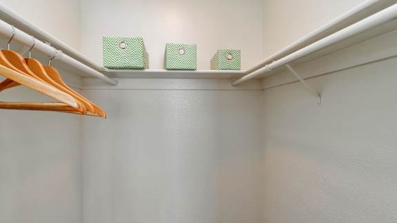 A white closet with a hanger and two green boxes on the shelf.