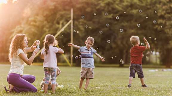 A group of children playing with bubbles in a park.