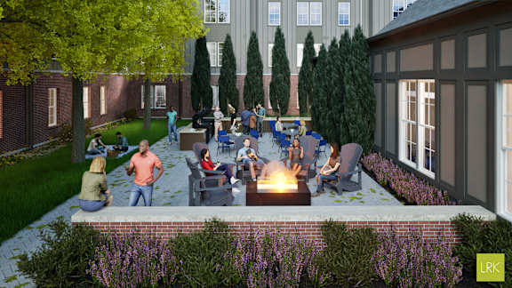 A group of people are sitting around a fire pit in a courtyard.