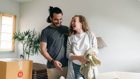 Laughing couple packing boxes inside a living room