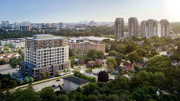 A modern multi-story building is surrounded by trees and other buildings in the distance.