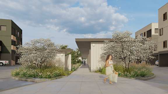 A woman in a white dress is walking down a sidewalk in front of a modern building.