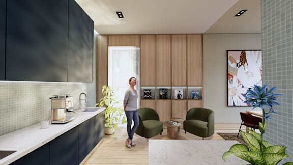 A woman is standing in a modern kitchen with a sink, a counter, and a chair.