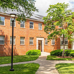 A red brick building with a tree in front.