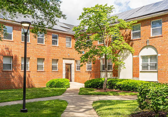 A red brick building with a tree in front.