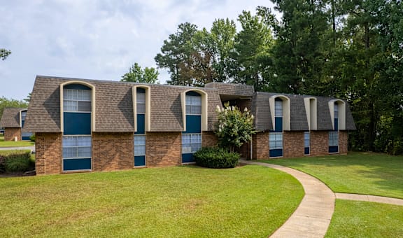A building with blue doors and windows is surrounded by greenery.