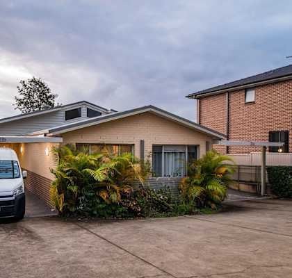 A white van is parked in a driveway in front of a house.