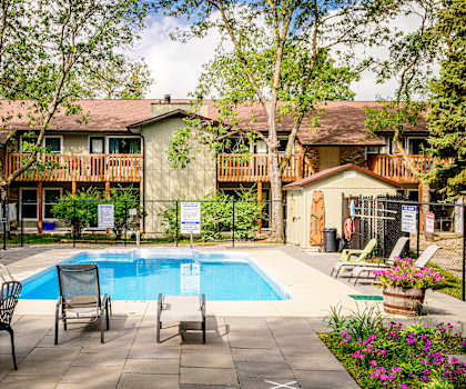 a swimming pool in front of a house with a pool table and chairs