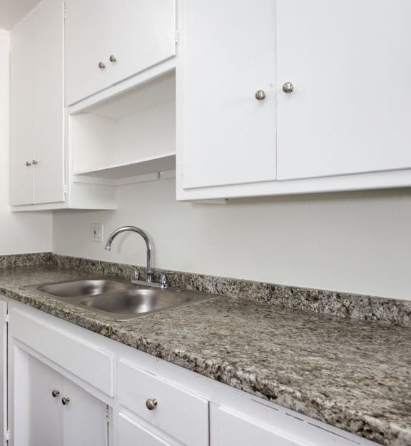 a kitchen with white cabinets and granite counter top and a sink