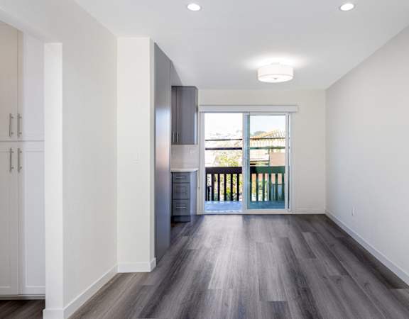 a living room with white walls and wooden floors and a balcony