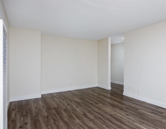 an empty living room with white walls and wood flooring