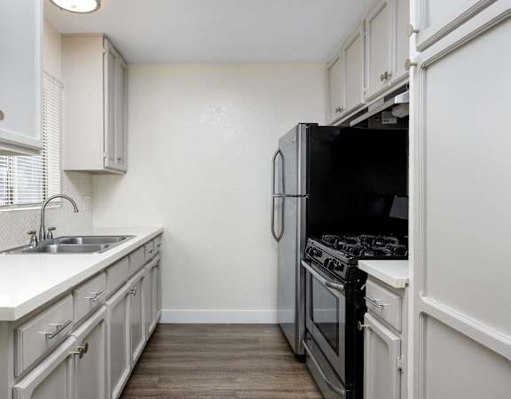an empty kitchen with white cabinets and a black stove and refrigerator