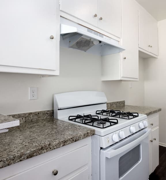 a kitchen with white appliances and granite counter tops and white cabinets