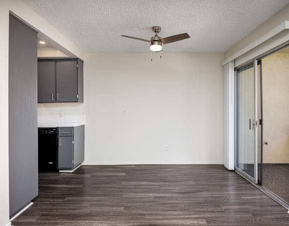 an empty living room with a ceiling fan and a kitchen