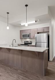 A kitchen with a refrigerator, microwave, and sink.