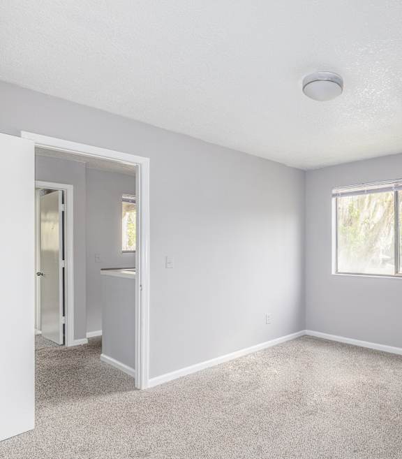 A room with a carpeted floor and a window.