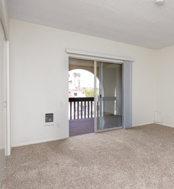 an empty living room with an open door to a balcony
