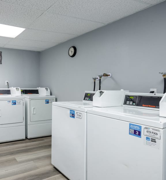 a row of washers and dryers in a laundromat with white machines