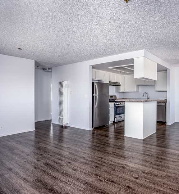 A kitchen with white cabinets and a wooden floor.